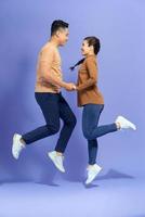 Attractive  partners holding hand jumping having fun isolated on purple background