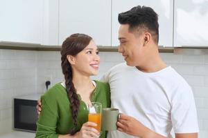 Attractive young woman and handsome man are enjoying spending time together while standing on light modern kitchen. photo