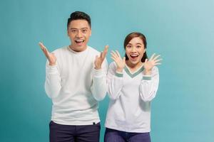 As like as two peas. A wonderful couple are posing with their palms near their chins, looking in the camera with surprised facial expressions photo