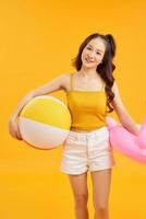 joven hermosa mujer juega con pelota de playa en verano sobre fondo naranja. foto