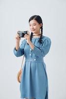 Young woman photographer taking picture for own collection and photo presentation on retro camera