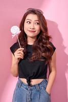 Happy woman in a black t-shirt holds a lollipop in her hand photo