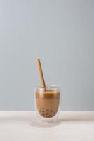 Chocolate buble tea glass with straw on blue background. photo