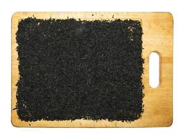 Black tea is placed on a wooden board in a thin layer to dry. Isolated on white background. photo