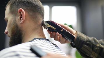 Barber trims back of head hair and neck of male client with comb and clippers video