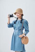 Portrait of a smiling young woman in summer hat standing with photo camera isolated over white background