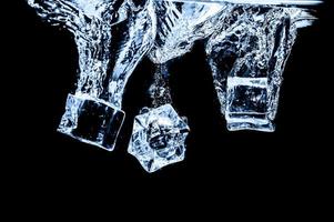 cubos de hielo en agua sobre fondo oscuro de estudio. el concepto de frescura con frialdad de cubitos de hielo. foto