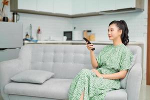 happy pretty girl with remote control watching tv photo