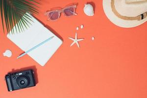 accesorios de playa planos, gafas de sol, sombrero, cámara con ramas de palma y conchas. foto