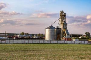 ascensor de granero moderno con silos de plata en la planta de procesamiento y fabricación de productos agrícolas para el procesamiento, secado, limpieza y almacenamiento de productos agrícolas, harina, cereales y granos. foto