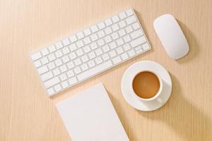 Flat lay, top view office table desk. Workspace with blank note book, keyboard, office supplies and coffee cup on wooden background. photo