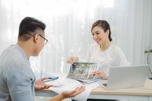 Real-estate agent showing house plans for client at office. photo