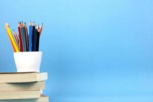 los elementos educativos aislados libros, bolígrafos, lápices sobre fondo azul claro. utilizado en el cartel de regreso a la escuela, diseño de plantilla de folleto