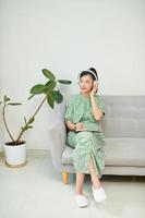 Young Asian woman listening music from headphones and writing note for her work idea in diary book. photo