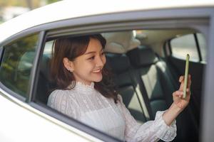 Business woman sitting on back seat in taxi car, taking selfie. photo