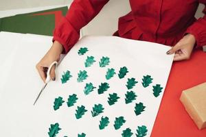 Woman cutting kraft paper and making envelopes at workshop, studio. Handmade and Xmas concept photo