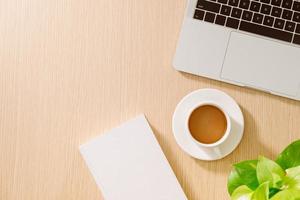 Office desk table with laptop, smart phone, cup of coffee, pen, pencil and notebook. Office supplies and gadgets on desk table. Working desk table concept. photo