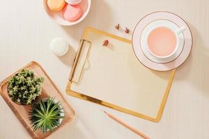 Women's home office workspace with clipboard, macaroons, pen, coffee mug on pastel background. Flat lay, top view lifestyle concept. photo