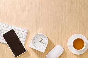 Modern white office desk with keyboard, mouse, clock, cellphone, pen and cup of coffee.Top view with copy paste. Business and strategy concept mockup. photo