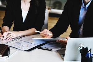 en la consulta, un asesor masculino usa un bolígrafo para señalar una tableta para explicar la reestructuración de ganancias a las propietarias de empresas. foto