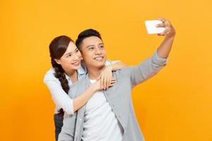 Photo of cheerful trendy charming cute nice couple of two people taking selfie smiling toothily hugging isolated yellow color background