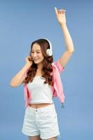 Pretty cool girl having fun and listens to music in the headphones, dancing over blue background. photo