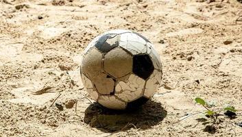 centrar una sola bola en la playa sin nadie. bola clásica rota en la arena. resumen de la afición y la vida deportiva. foto