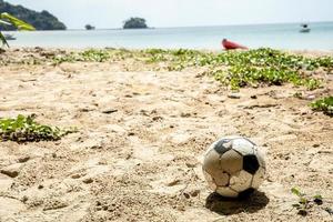 sola pelota en la playa sin nadie. bola clásica rota en la arena. resumen de la afición y la vida deportiva. foto