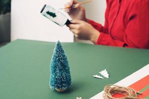 Close up of female hands painting the Christmas tree paper. Flat lay. photo