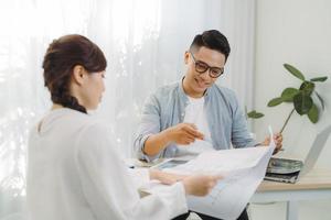 agente inmobiliario muestra un proyecto de construcción en una tableta digital a un joven asiático. foto