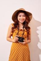 Image of young photographer woman isolated over beige background wall holding camera. photo