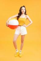 linda chica con pelota de playa, aislada de fondo amarillo foto