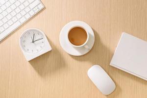 Modern white office desk with keyboard, mouse, notebook, clock and cup of coffee. Top view with copy paste. Business and strategy concept mockup. photo