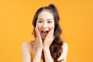 young pretty surprised woman with opened mouth standing with open palms, isolated on yellow background photo