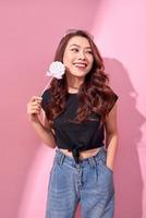 Fashion woman having fun with lollipop over pink background photo