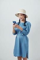 Cheerful young woman reading text message on her cell phone against white background photo