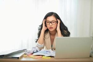 trabajo remoto, tecnología y concepto de personas - mujer joven estresada con computadora portátil y papeles que trabajan en la oficina del hogar foto