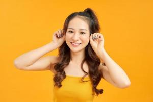 Portrait happy young asian woman feeling carefree laughing positive emotion on yellow background photo