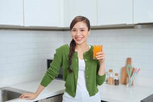 Young healthy asian woman drinking orange juice photo