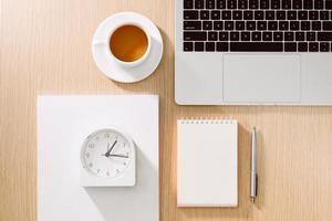 Office desk table with laptop, smart phone, cup of coffee, pen, pencil and notebook. Office supplies and gadgets on desk table. Working desk table concept. photo