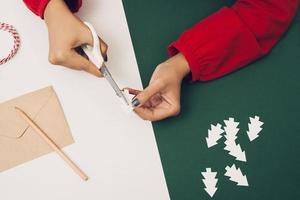 Woman cutting Christmas tree paper with envelopement and color paper. Noel diy photo