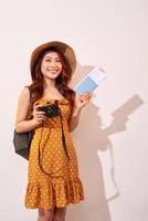 Expressive tourist woman in summer casual clothes, hat holding passport, tickets isolated on beige background. Female traveling abroad to travel weekends getaway. Air flight journey concept photo