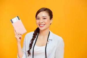 Expressive tourist woman in summer casual clothes holding passport, tickets isolated on yellow orange background. photo