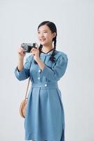 joven asiática, sosteniendo una cámara antigua y tratando de tomar una foto