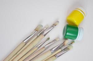 Top view of closed cans of green and yellow paint and artistic cetin paint brushes for painting on light background photo