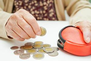 anciana jubilada que cuenta monedas y se preocupa por los gastos mensuales y el pago de la tarifa de tratamiento.