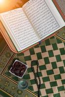 iftar time dátiles secos, vaso de agua del sagrado corán y tasbih en la alfombra de oración sarajevo foto
