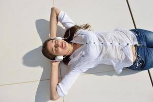 girl listening to the music on white headphones photo