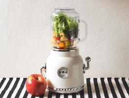 white vintage blender or smoothie maker machine  with an apple on  black and white stripe table cloth and white wall. Healthy drink making. photo