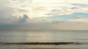 aereo jet sull'approccio finale prima di atterrare all'aeroporto internazionale di phuket, bellissime onde sulla spiaggia, rallentatore. video